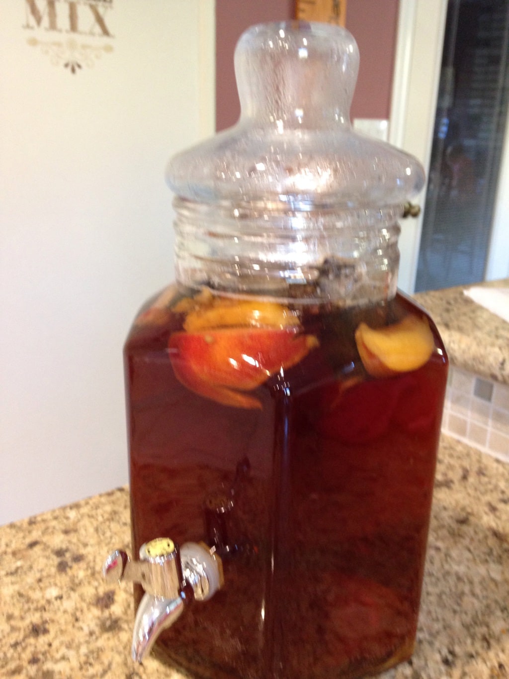 A fresh batch of nectarine-infused sun tea in a glass drink dispenser. 