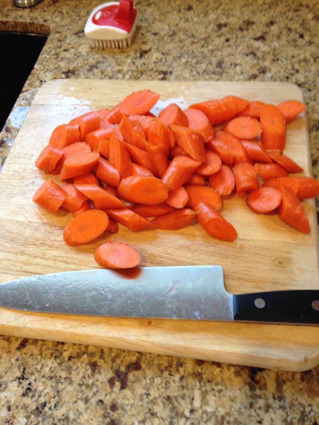 A cutting board with sliced carrots, ready to be roasted.