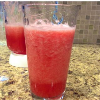 A glass of watermelon aqua Fresca in front of a blender.
