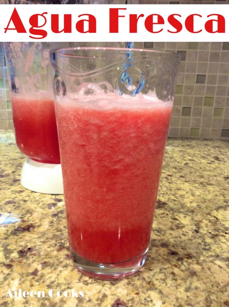 A glass of watermelon aqua Fresca in front of a blender.