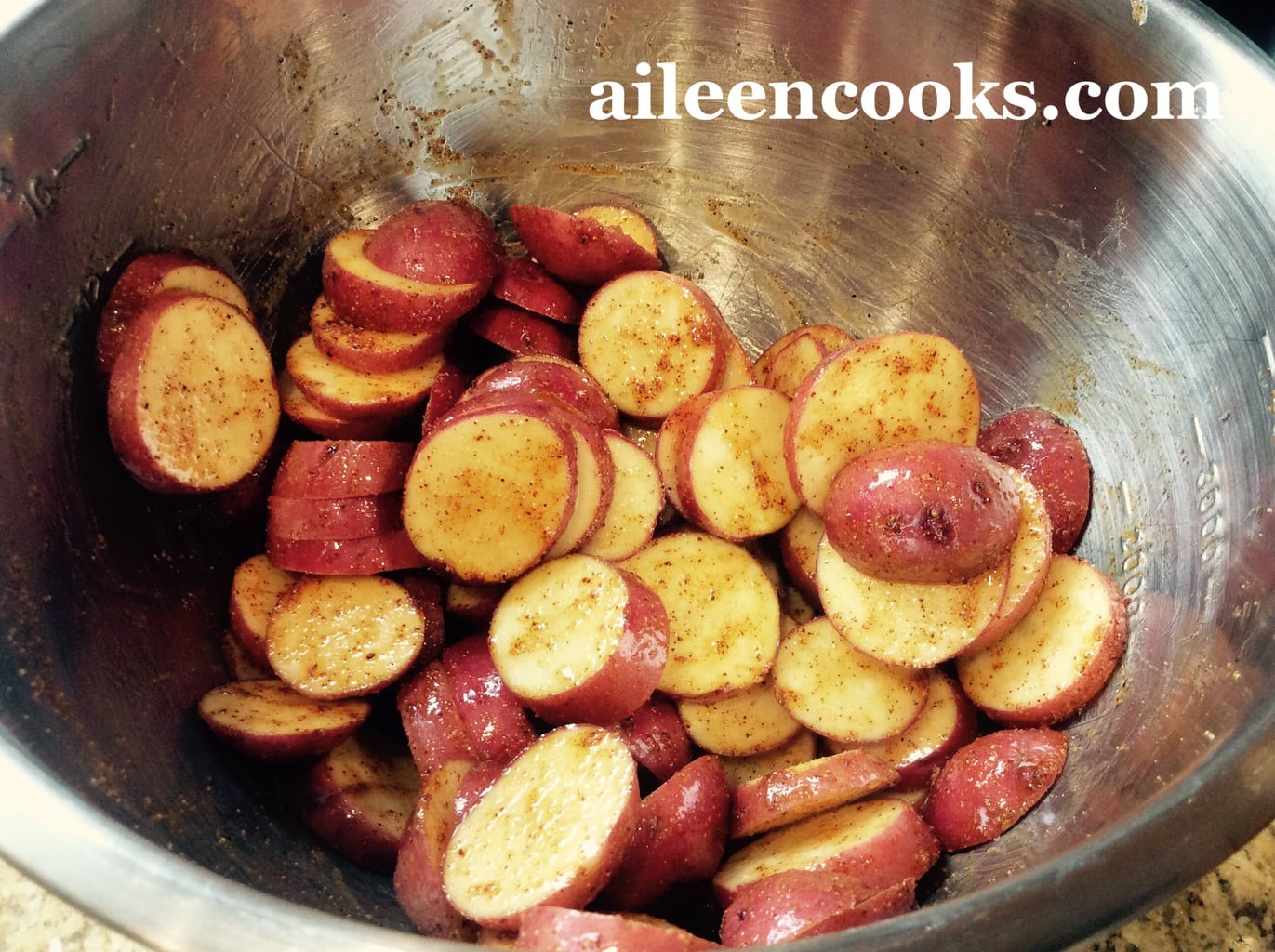 Sliced red potatoes tossed with olive oil and spices, ready to be transformed with the roasted red potatoes recipe.