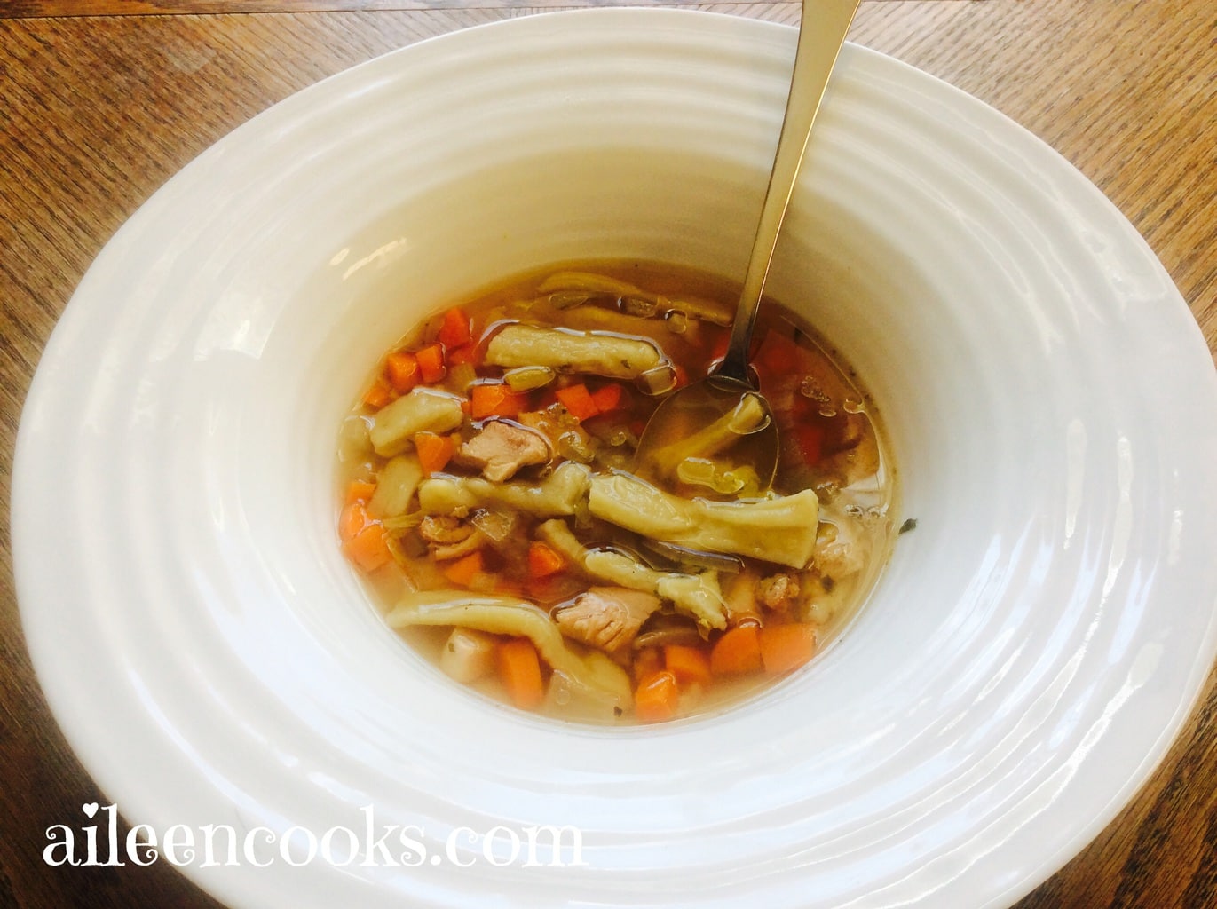 A white bowl filled with crockpot chicken and egg noodles with a spoon sticking out.