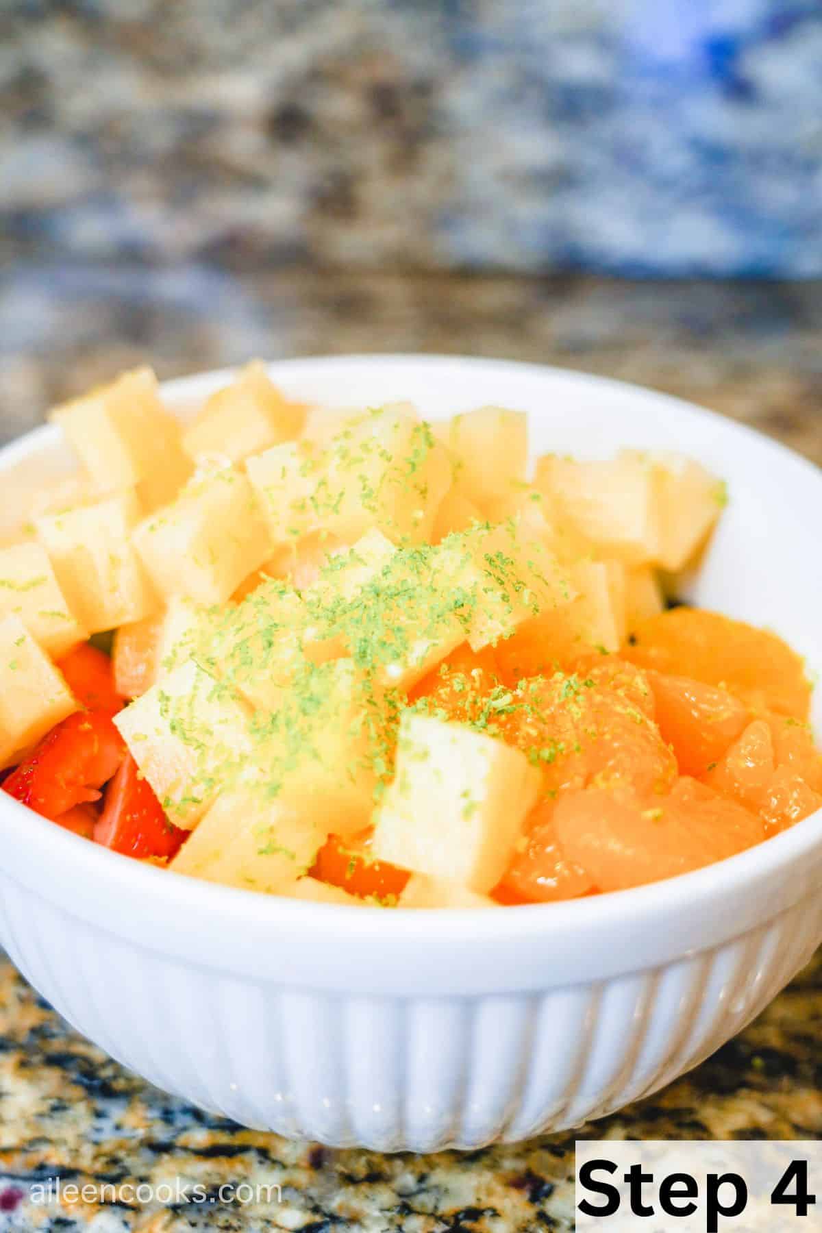 A bowl of fruit topped with lime zest.