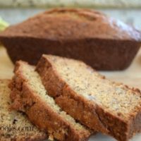 Three slices of banana bread in front of a loaf of banana bread.