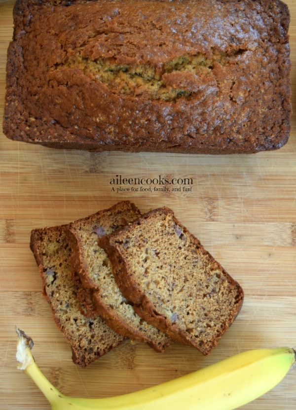 Overhead shot of loaf of banana bread next to three slices of banana bread