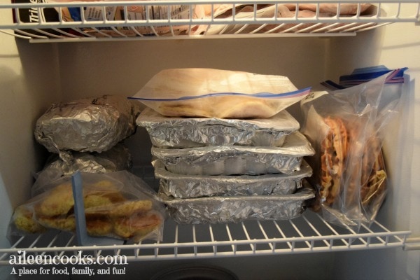 The inside of a freezer filled with several frozen casseroles and soups.