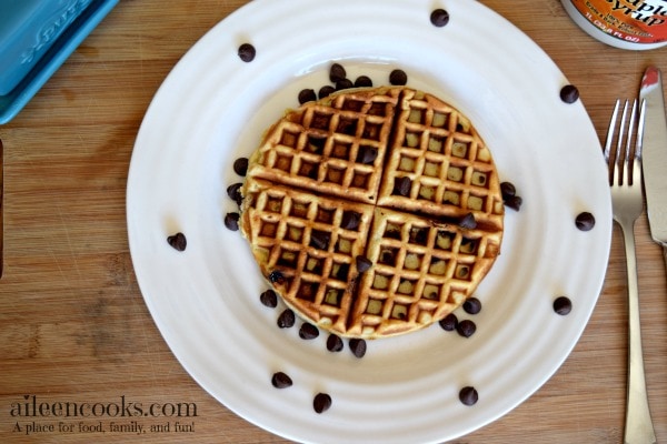 Overhead shot of a completed chocolate chip waffles recipe next to a fork and knife.
