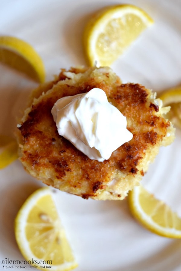 Plate of stacked tilapia fish cakes surrounded by lemon wedges.