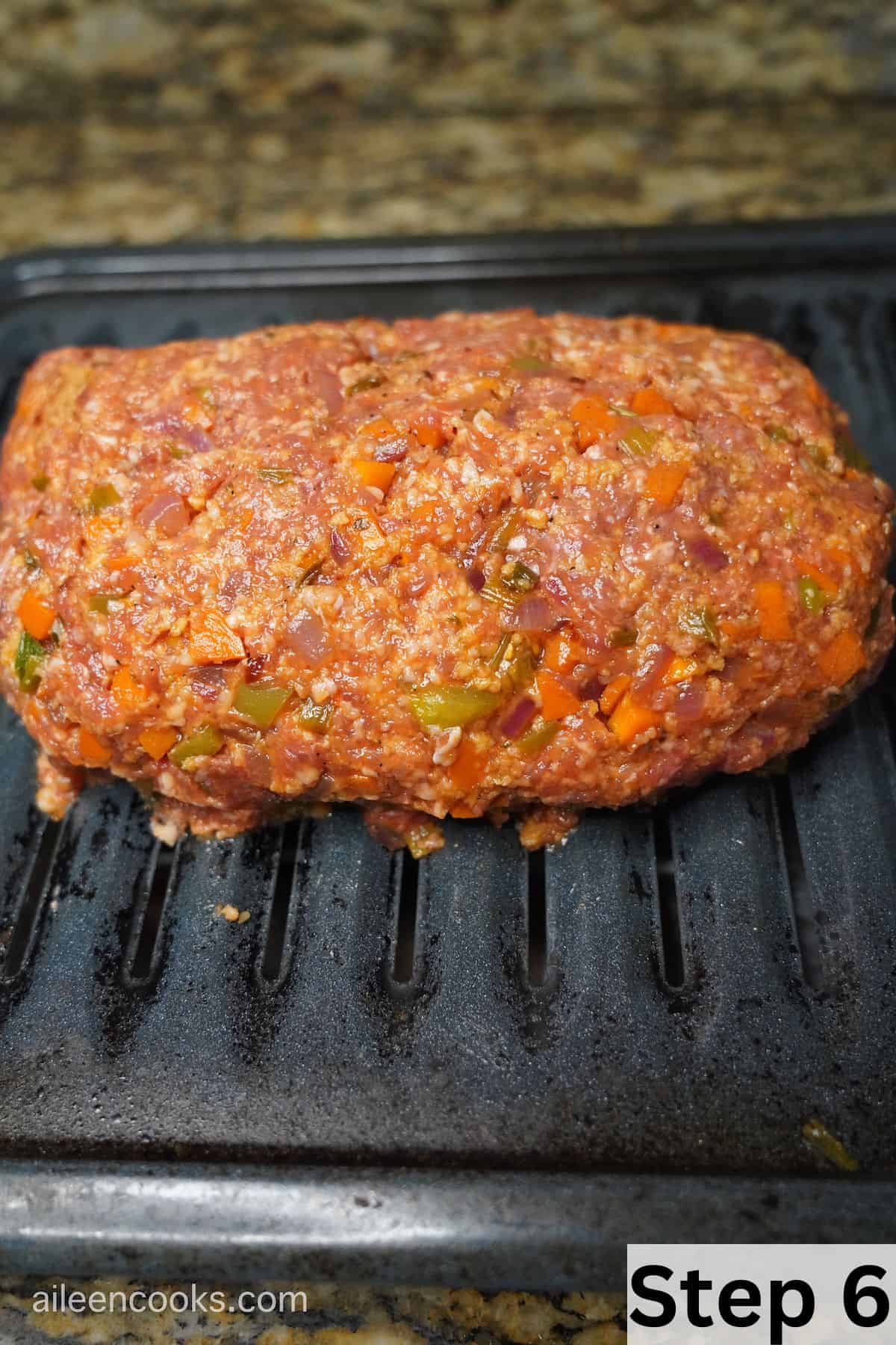 A meatloaf shaped on top of a broiler pan.