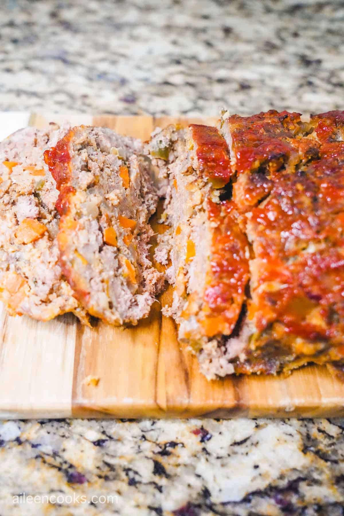 A meatloaf sliced up on a wooden cutting board.