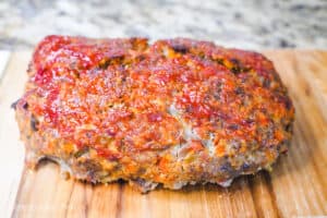 A freshly baked meatloaf on a wooden cutting board.