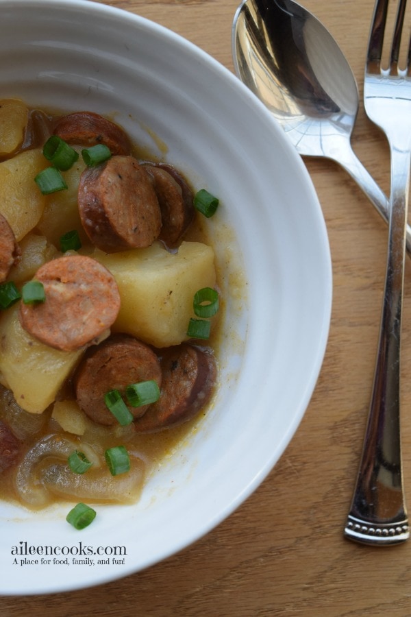 Cajun Sausage recipe in a white bowl with a fork and knife to the side.