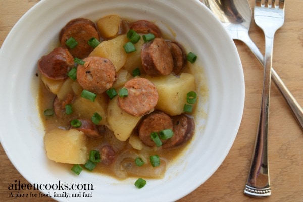 Crockpot Cajun Sausage and Potatoes in a white bowl and topped with green onions.