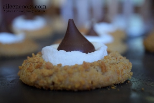 S'mores blossom cookies topped with toasted marshmallows and Hershey's kisses. Perfect blossom cookie recipe for a Christmas, Valentine's Day, or cookie exchange Recipe from aileencooks.com.