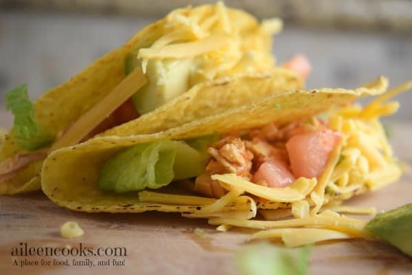 instant pot salsa chicken tacos in crispy taco shells with fresh tomato and lettuce