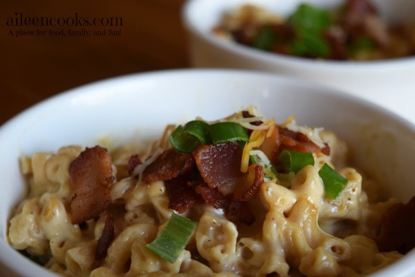 Close-up to a bowl full of instant pot macaroni and cheese recipe and loaded with bacon and green onions. 