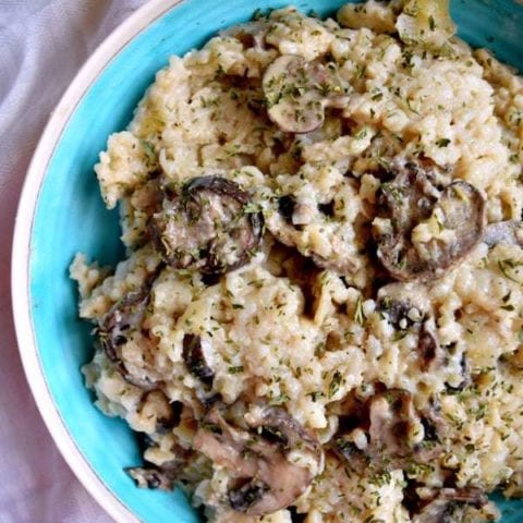 Blue bowl with instant pot mushrooom risotto inside on a white tablecloth