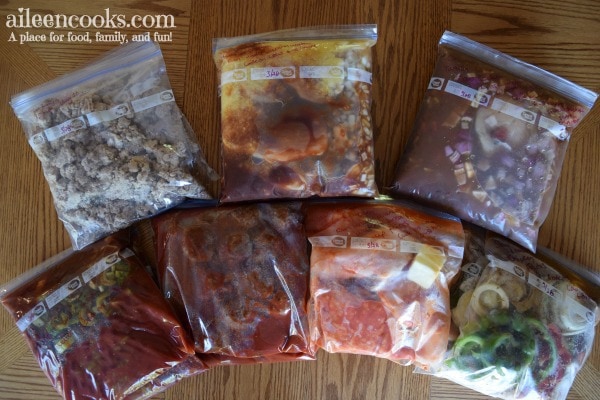 An overhead shot of 14 crockpot freezer meals frozen in ziplock bags.