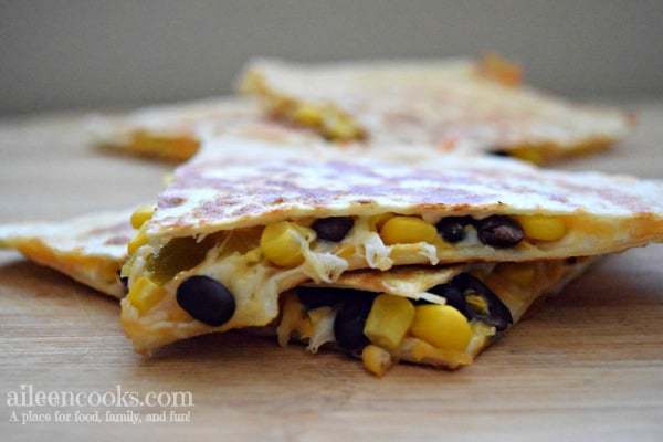black bean and corn quesadillas cut into triangles with melting cheese dripping out.