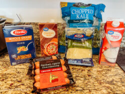 All of the ingredients for one pot smoked sausage and kale pasta on a kitchen counter.