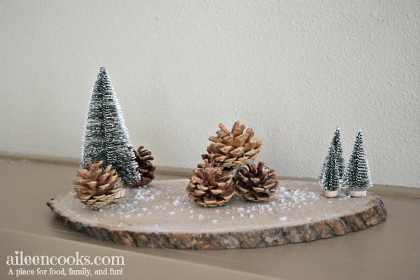 Create these festive and rustic winter centerpieces with wood rounds, sisal trees, pine cones, and craft snow!