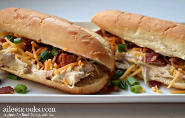 Close up of instant pot crack chicken on a roll with cheese, scallions, and bacon.