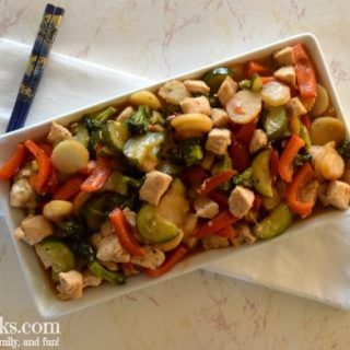 platter holding chicken stir fry sitting on top of white towel on a marble counter top