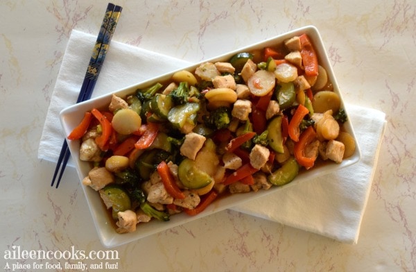 platter holding chicken stir fry sitting on top of white towel on a marble counter top