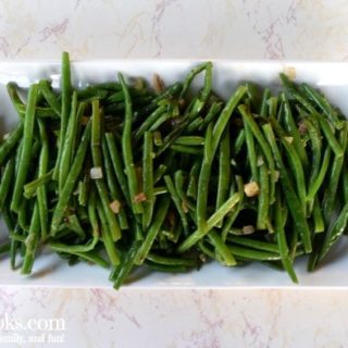 White platter filled with green beans and caramelized shallots