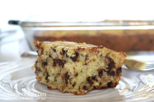 close up of slice of banana chocolate chip cake with whole cake in the background