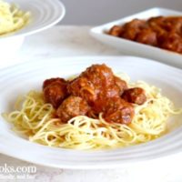 bowl of spaghetti, platter of italian meatballs, and plate with spaghetti, meatballs, and marinara.