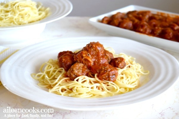 bowl of spaghetti, platter of italian meatballs, and plate with spaghetti, meatballs, and marinara.