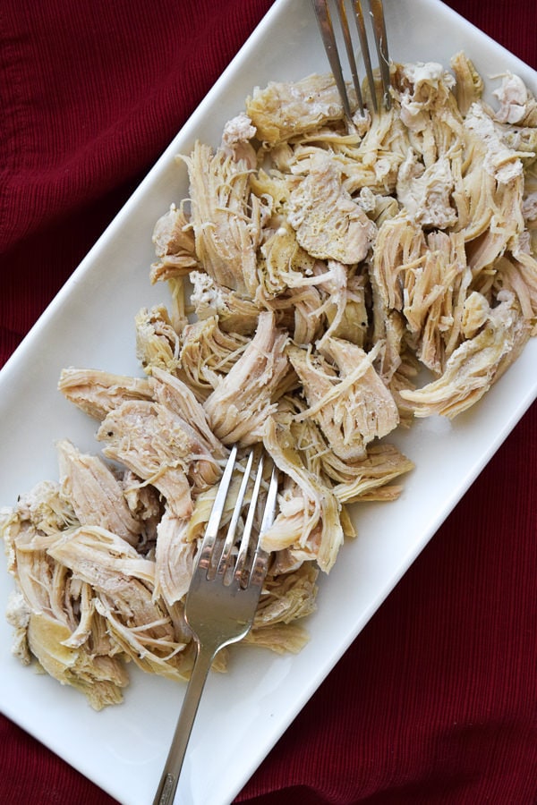 Easy instant pot shredded chicken made with frozen chicken served on white dish over red napkin.