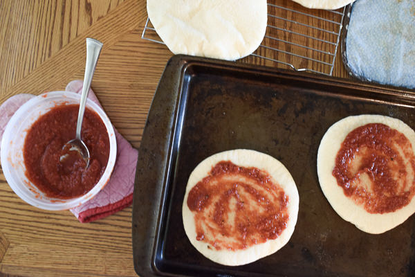 Individual pizza dough with sauce spread and almost ready to be frozen for homemade frozen pizzas. 