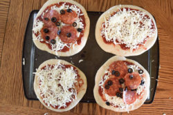 4 homemade freezer pizzas. 2 are plain cheese and 2 are pepperoni and olive, all sitting on top of a large cookie sheet.