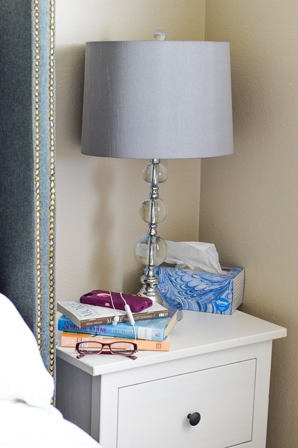 nightstand with books, glasses, and cell phone.