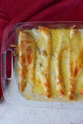 chicken enchiladas in a white sauce sitting in a baking dish.