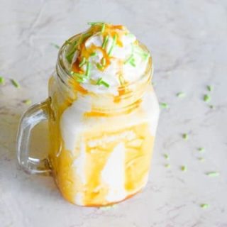 Caramel Apple Milkshake topped with whipped cream, caramel sauce, and green sprinkles.