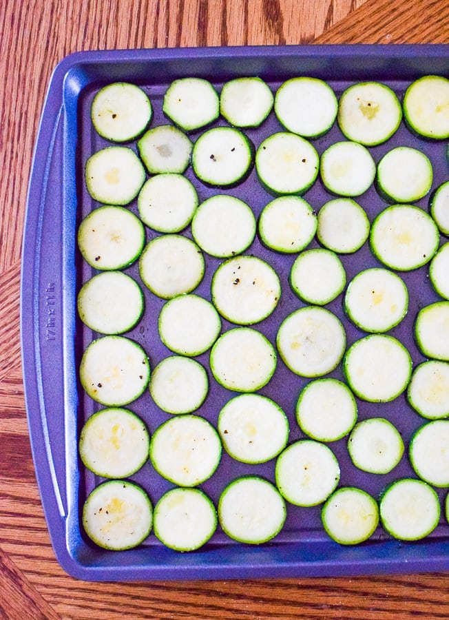 Cookie sheet with sliced rounds of zucchini ready to be baked into parmesan zucchini rounds.