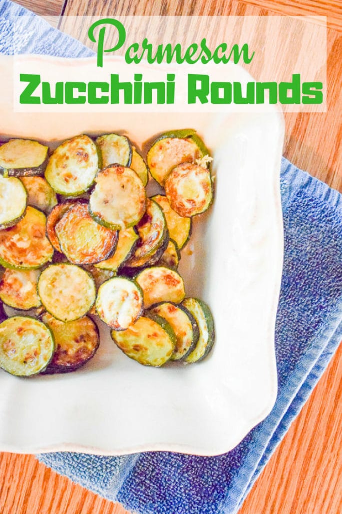 White baking dish on a blue dish towel filled with parmesan zucchini rounds.