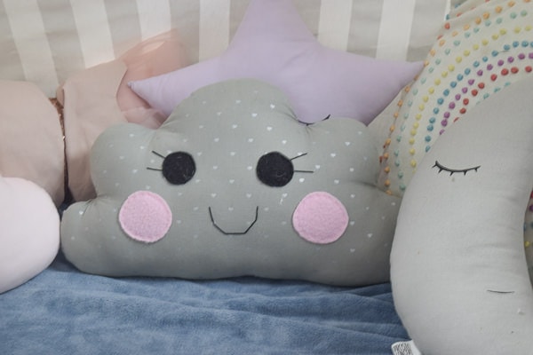 grey cloud pillow with pink cheeks inside a reading nook