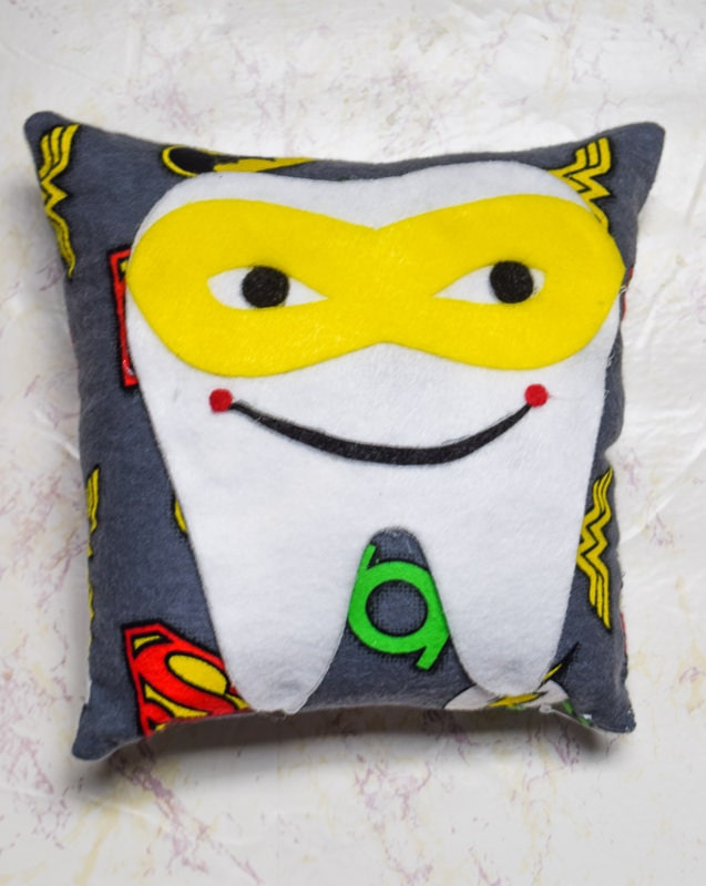 Superhero tooth fairy pillow made with the cricut maker using cotton superhero printed fabric and various colors of felt.