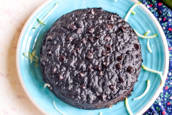 overhead shot of instant pot chocolate zucchini bread on a blue plate surrounded by shredded zucchini