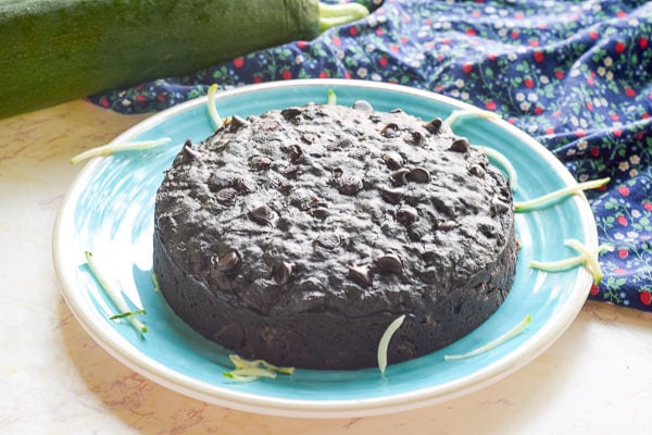 instant pot zucchini bread on a blue plate with large zucchini in background