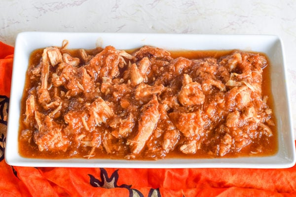 White platter filled with instant pot white chicken over orange tropical fabric.