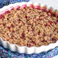 Plum crisp made with fresh plums sitting on a blue floral napkin over a white countertop