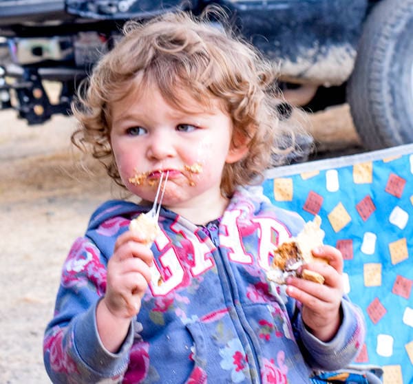 Toddler girl eating a s'more while camping at Casini Ranch campground.