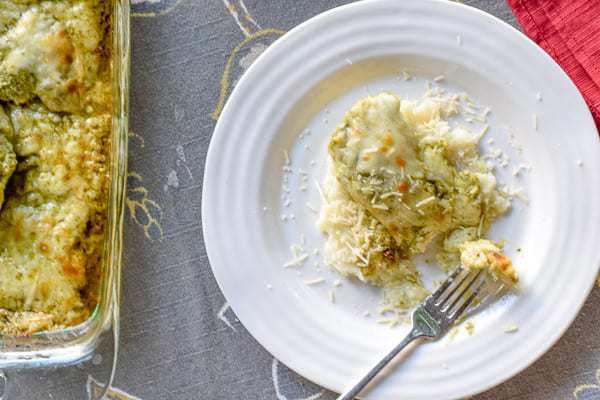 Baked Pesto Chicken Recipe on a white plate with a forkful of food.