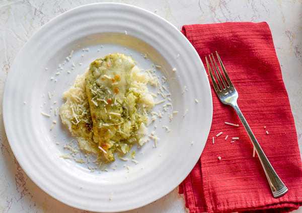 Baked pesto chicken on top of mashed potatoes and topped with Parmesan cheese.