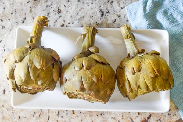 Three instant pot artichokes on a white platter. 